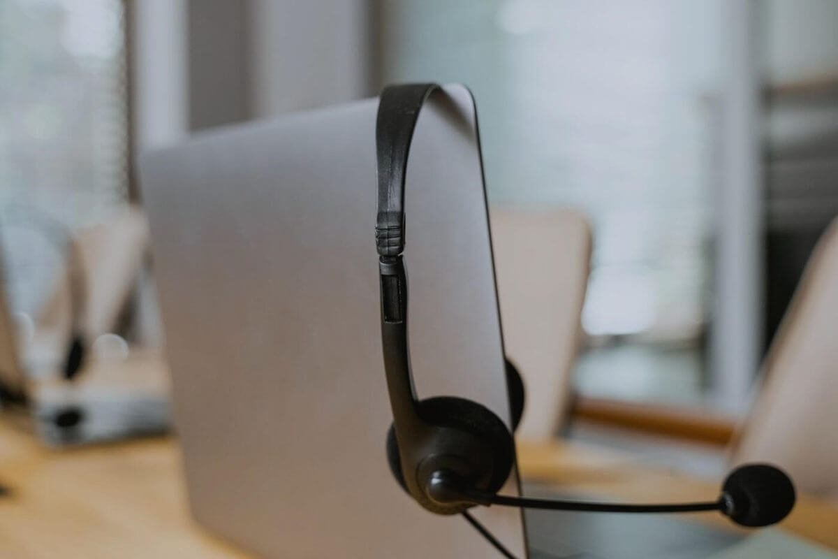 Un auricular de atención al cliente colgado sobre la pantalla de una laptop, en una oficina vacía